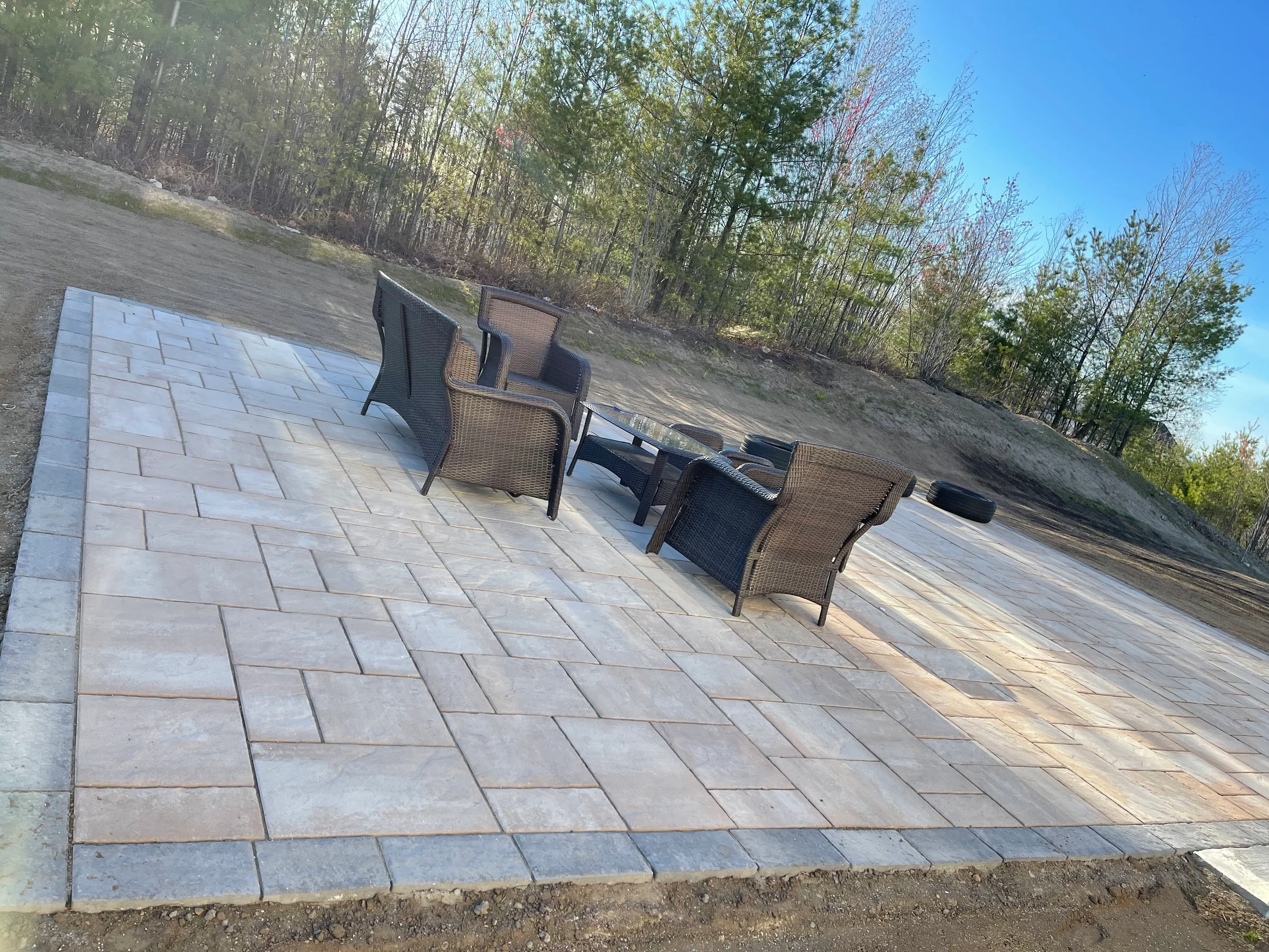 Completed rectangular paver patio furnished with outdoor chairs and a table