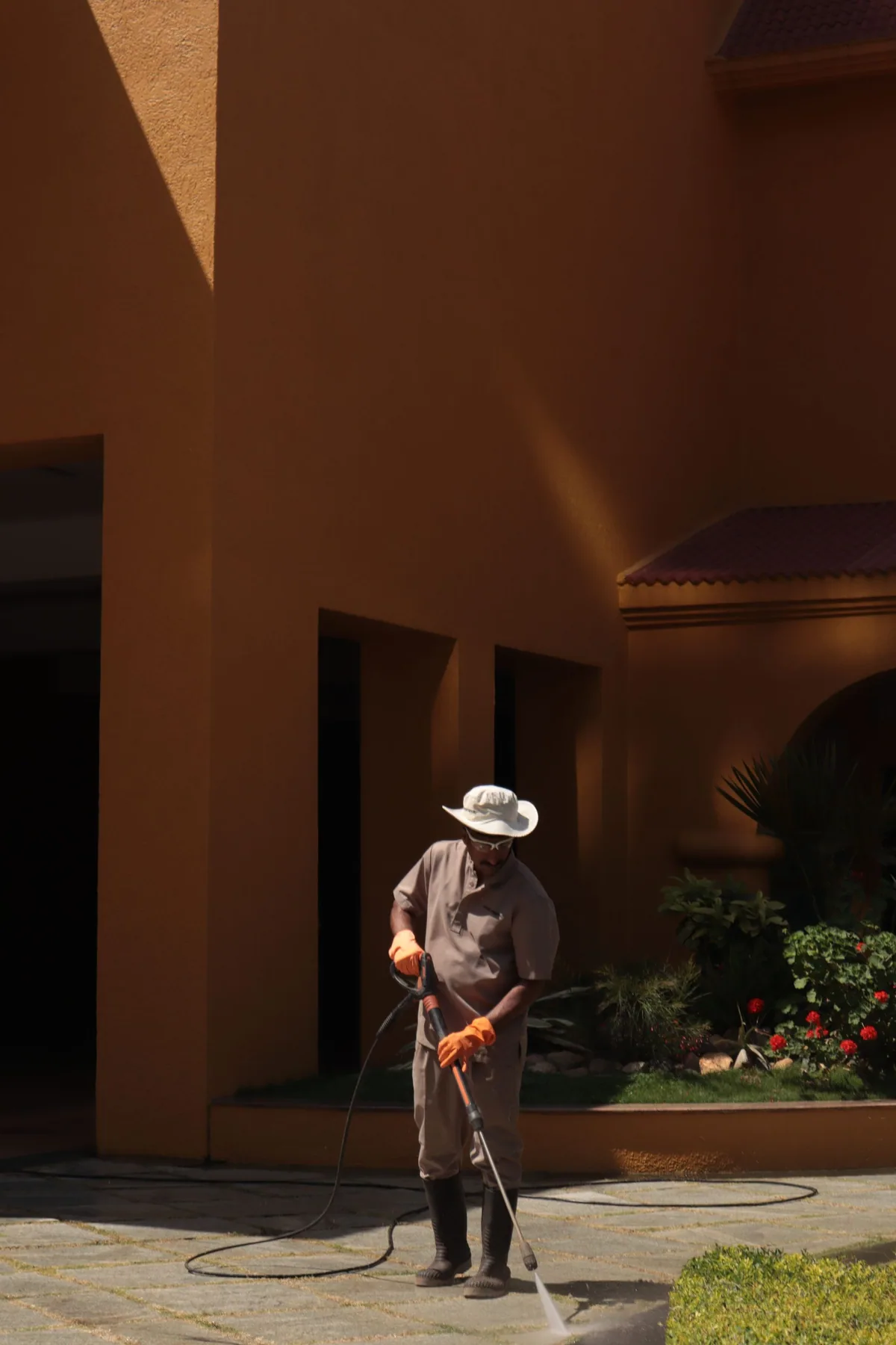 Landscaping professional pressure washing a paved outdoor surface